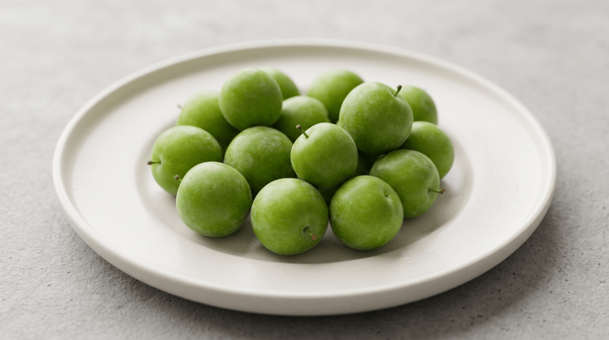 Fresh green plums arranged on a white plate